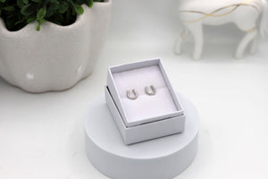 A pair of rhodium-plated sterling silver horseshoe earrings with cubic zirconia diamonds, presented in a white jewellery box