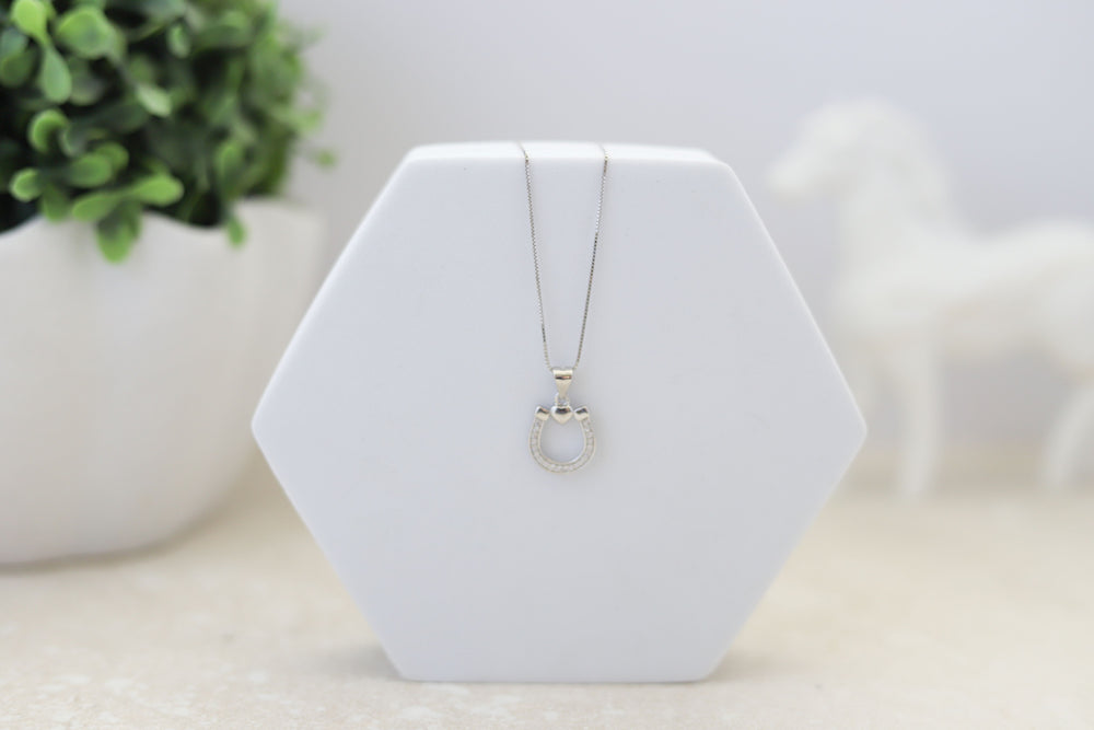 A sterling silver pendant in the shape of a horseshoe and heart with simulated diamonds