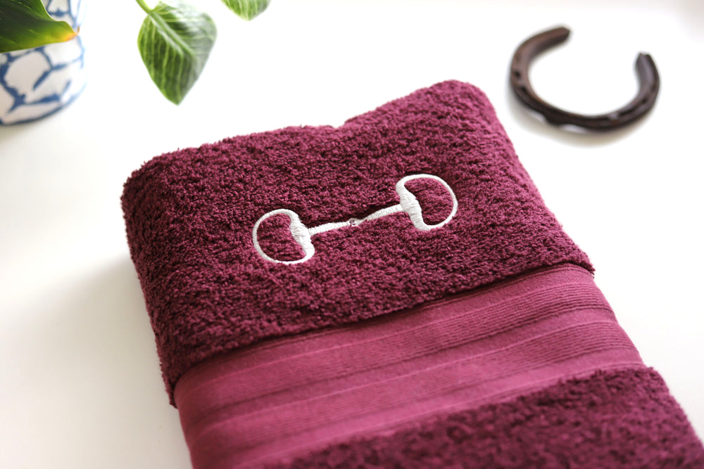 Close up of embroidered snaffle bit on burgundy bath towel