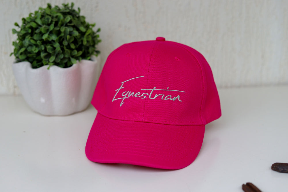A hot pink baseball cap with Equestrian embroidered in white on the front of the cap.