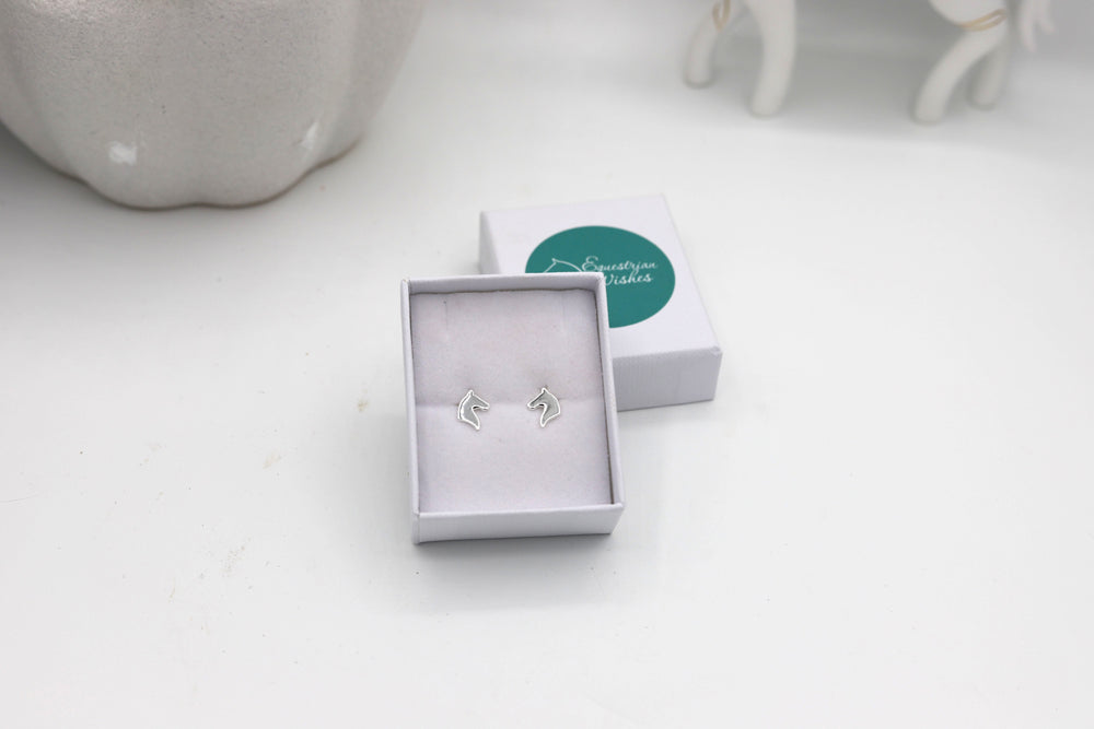 A pair of sterling silver horsehead outline push back earrings displayed in a jewellery box