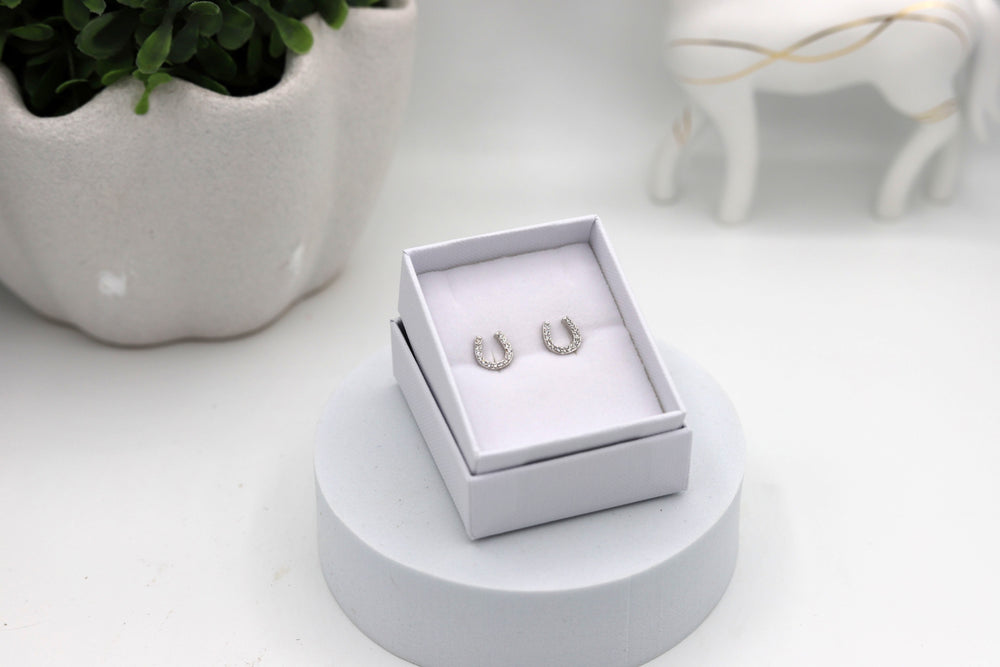 A pair of rhodium-plated sterling silver horseshoe earrings with cubic zirconia diamonds, presented in a  white jewellery box