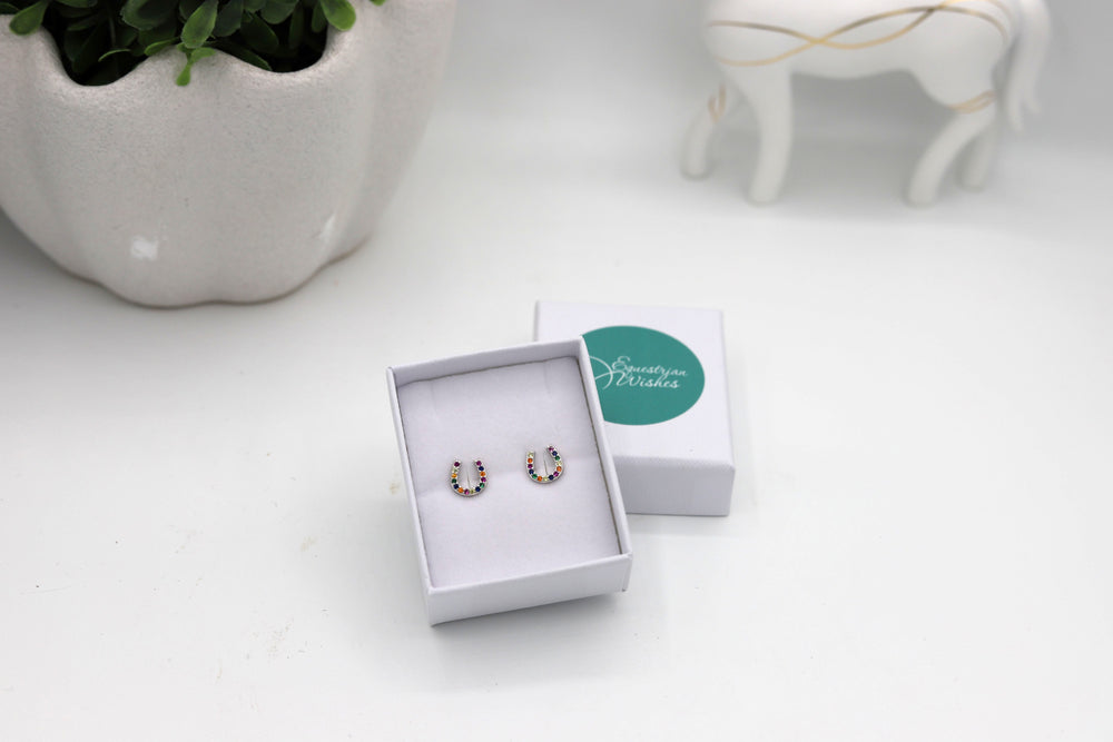 A pair of horseshoe earrings with colorful simulated diamonds, presented in a white jewellery box 