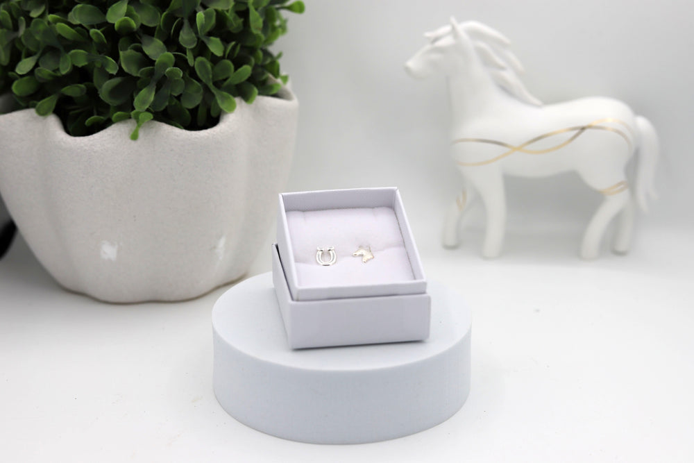 A pair of sterling silver horsehead and horseshoe earrings in a white jewellery box