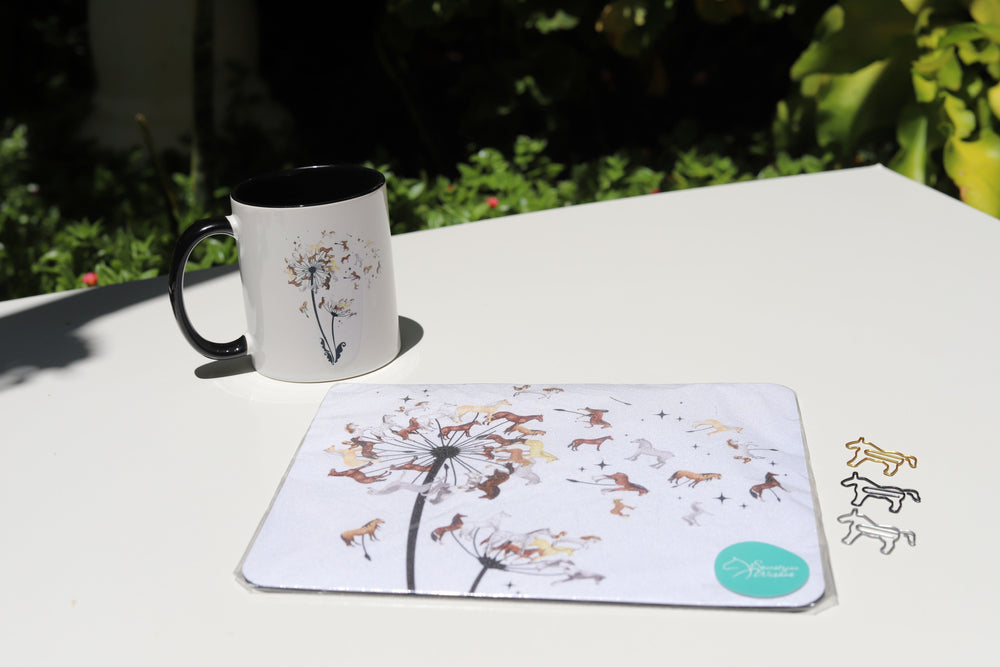 A set that contains a mug and a mouse pad, both with the same image of a dandelion that consist of horses and 3 horse paperclips