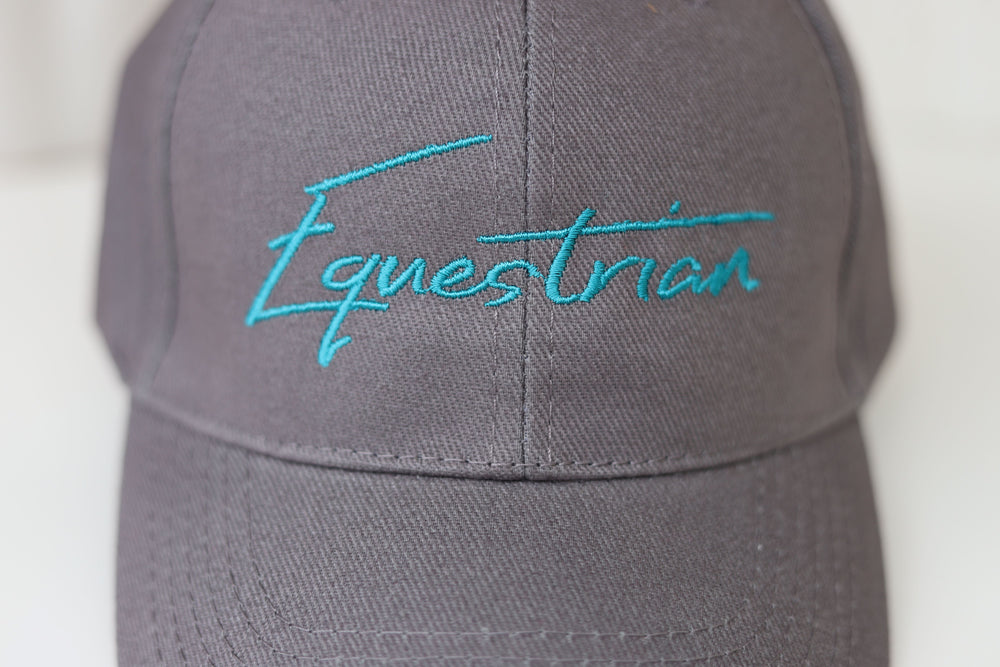 Close up of the embroidered word 'Equestrian' on a grey baseball cap