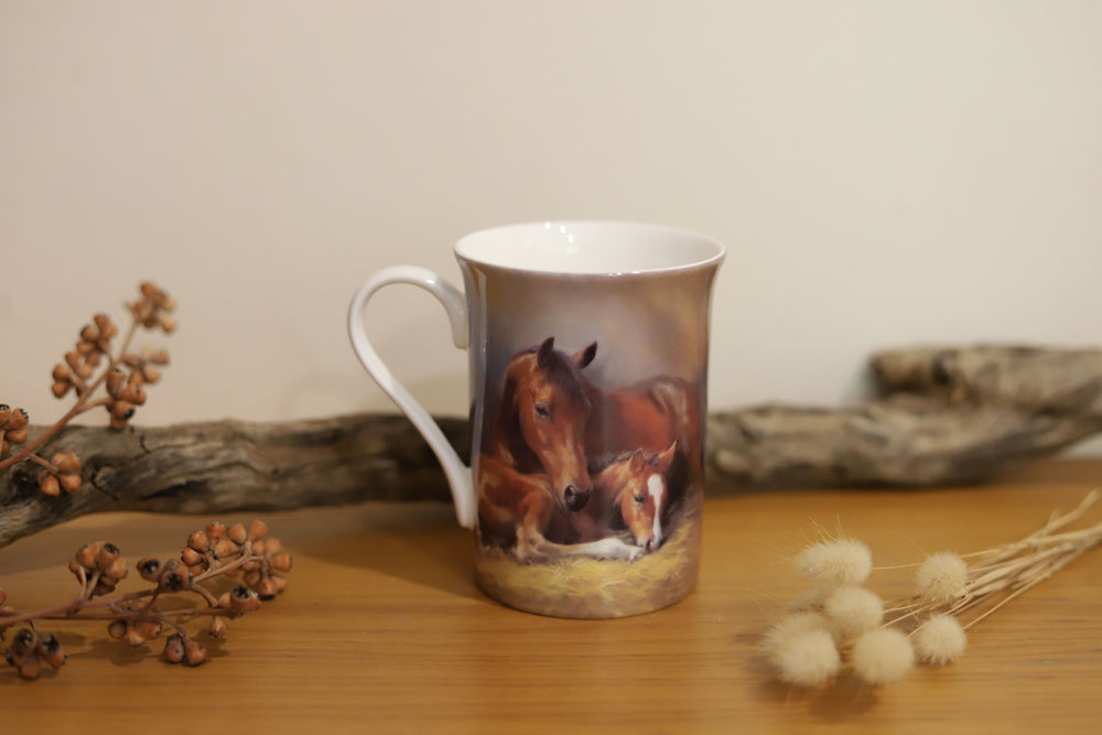 Front view of a mug from the 'Mares and Foal' collection displaying a mare and foal lying in a stable