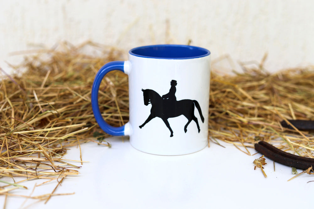 A white ceramic mug with blue trim displaying a dressage rider - equestrian gifts Australia