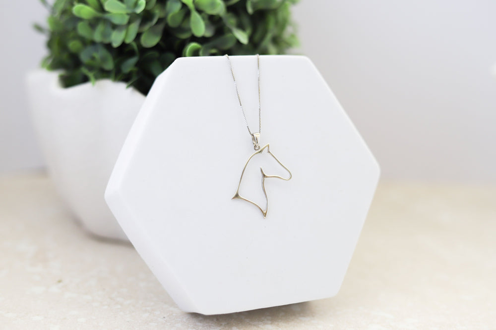 Angled view of a sterling silver horse head outline with a sterling silver chain