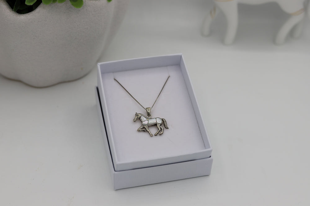 A sterling silver horse pendant with mother of pearl inlay, presented in a white jewelry box with a chain attached.