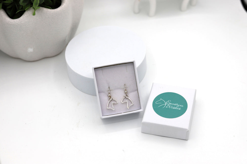 A pair of sterling silver horsehead outline hook earrings displayed in a jewellery box